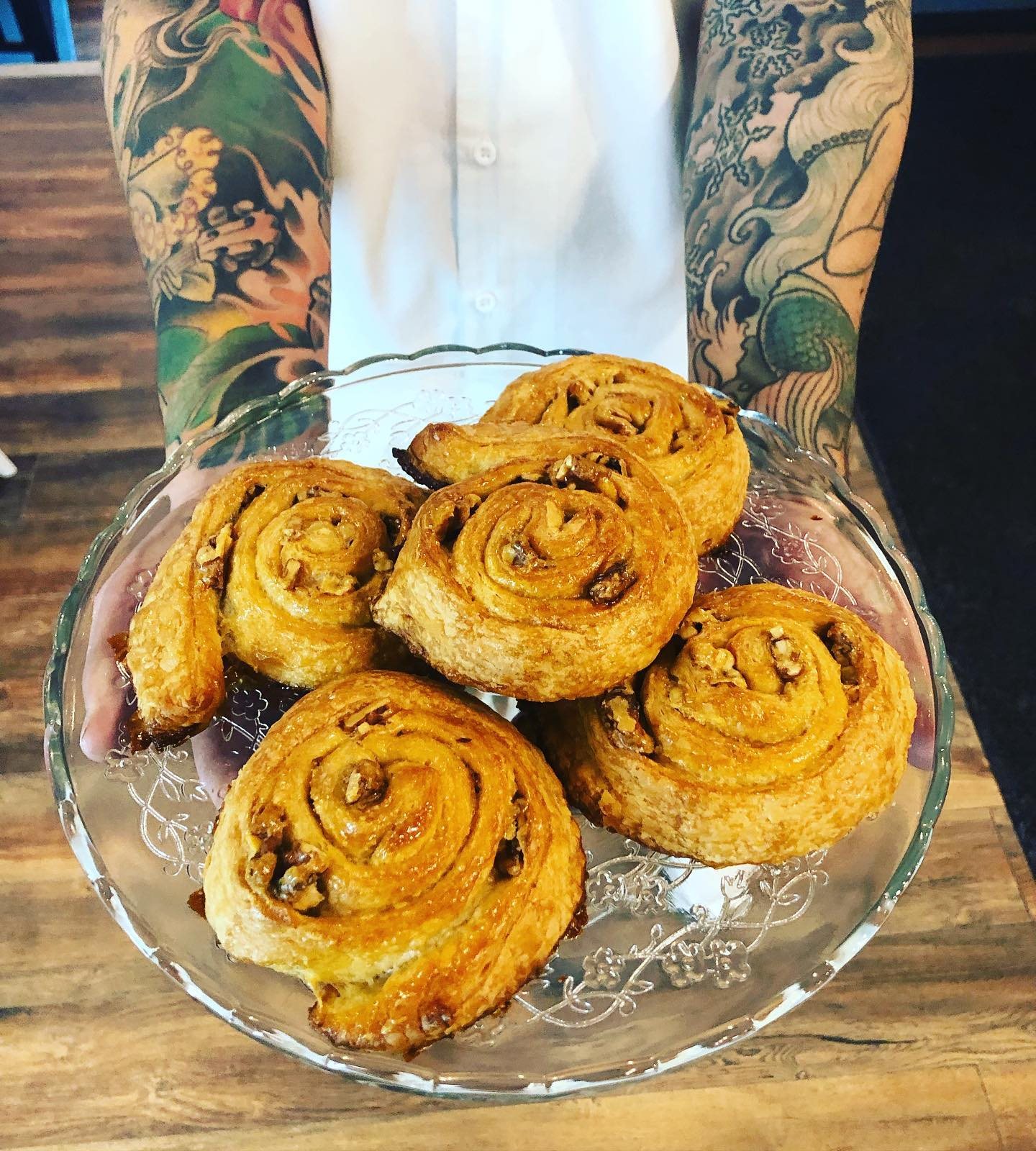 Un plat de brioches aux pacanes tenu par un boulanger