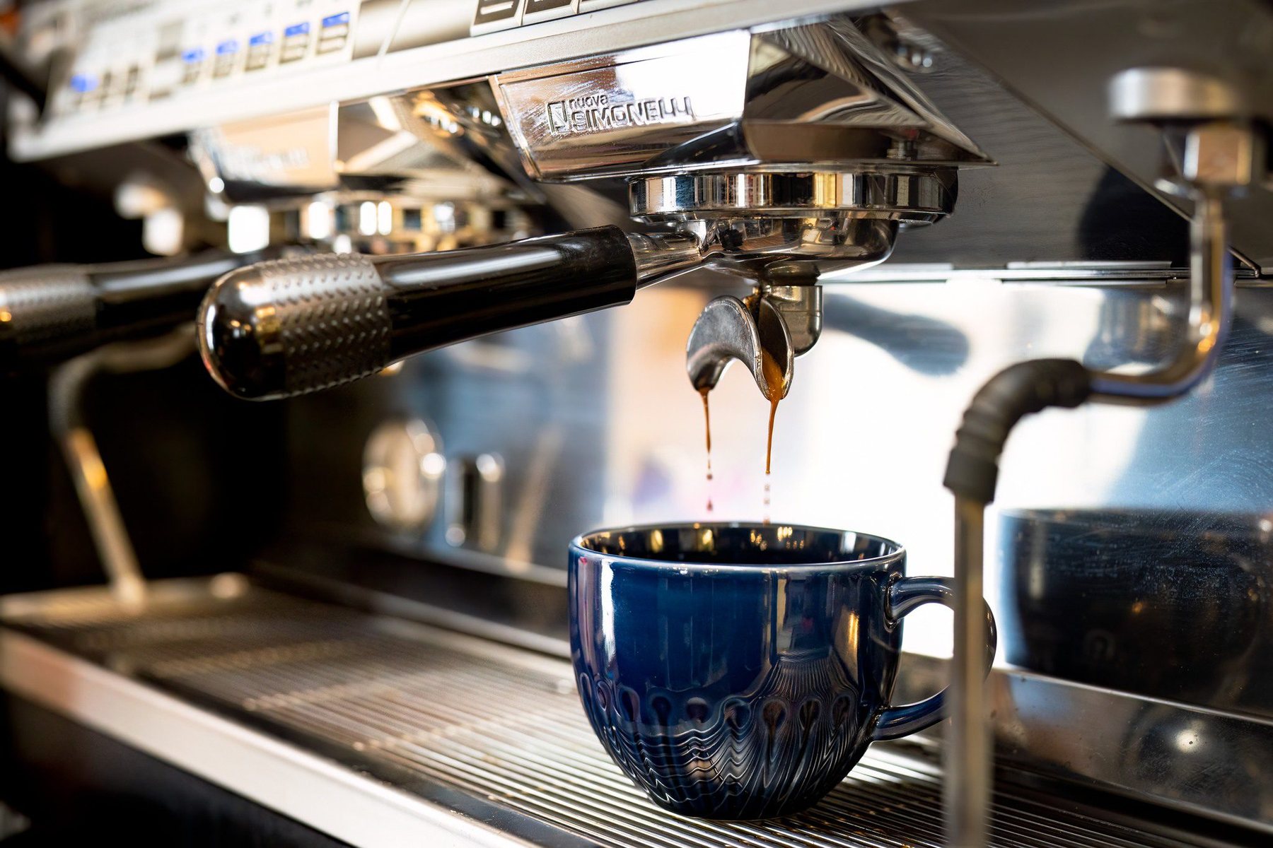 Un espresso qui coule dans une tasse bleue, sous la machine