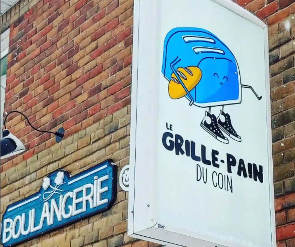 L’enseigne de la boulangerie sur le mur de brique : le grille-pain bleu en espadrilles